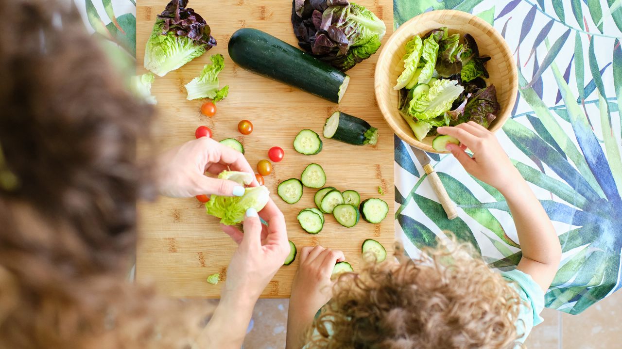 top view of a mother and son prepare vegetables for salad
