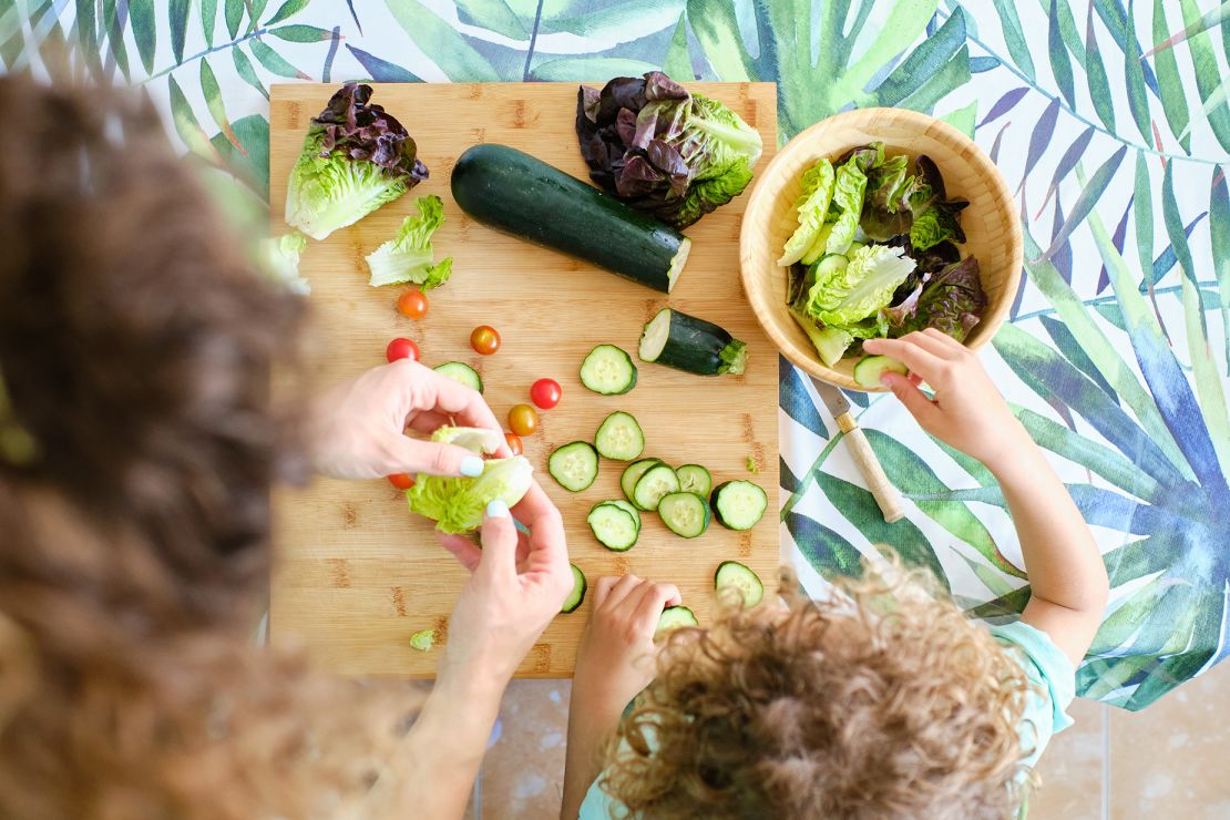 top view of a mother and son prepare vegetables for salad