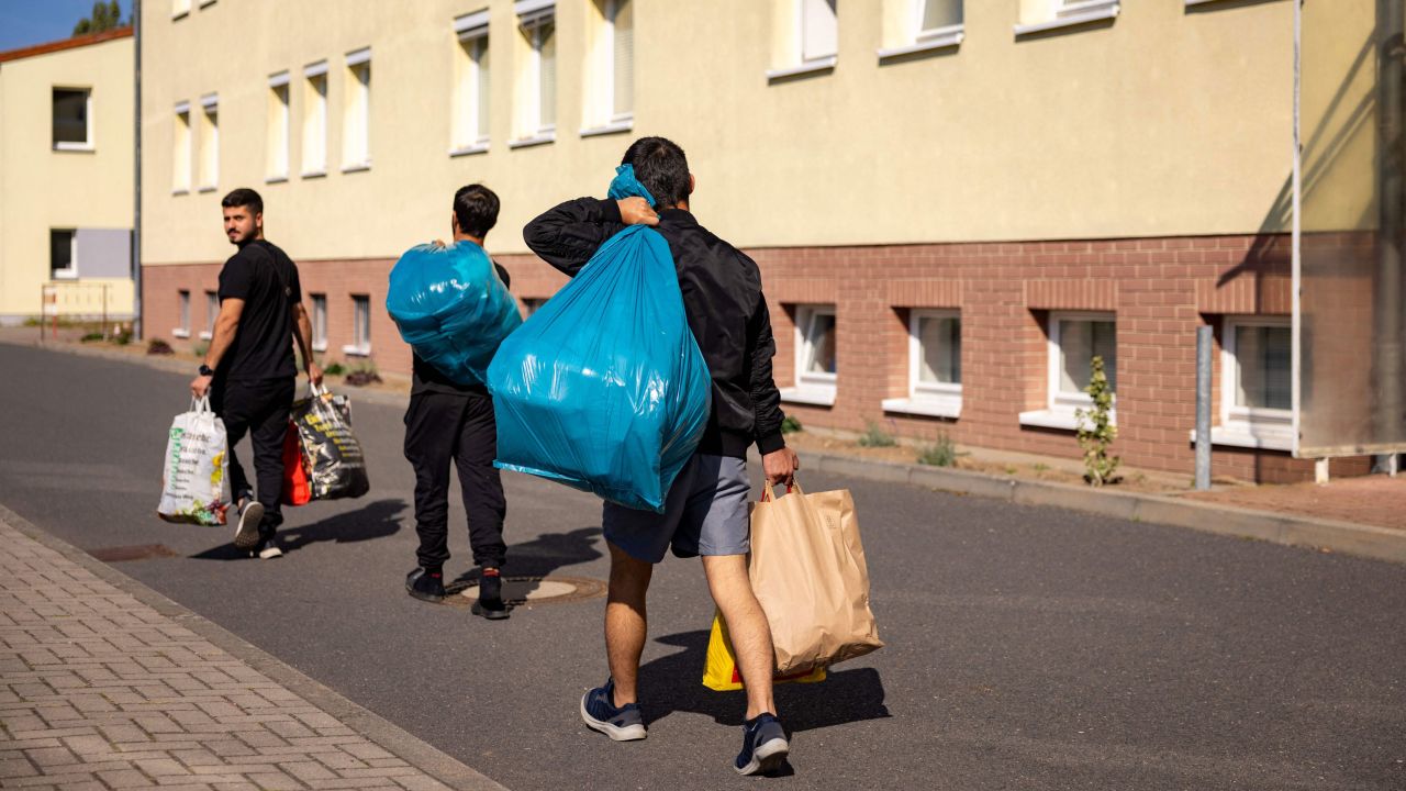 Migrants walk past a housing block at Brandenburg's Central Immigration Authority center, in Eisenhuttenstadt, eastern Germany. 