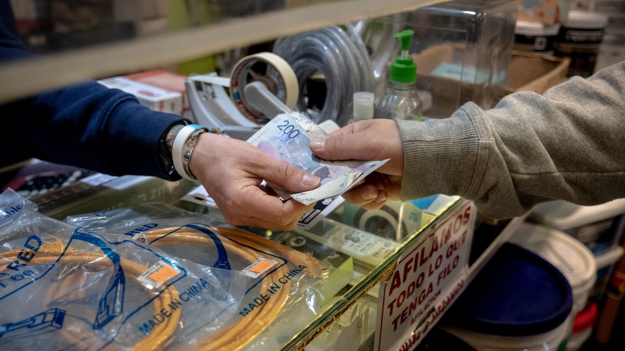A worker receives Argentine peso banknotes in a shop in Buenos Aires on Sept. 26, 2023. Milei has proposed dollarizing Argentina.
