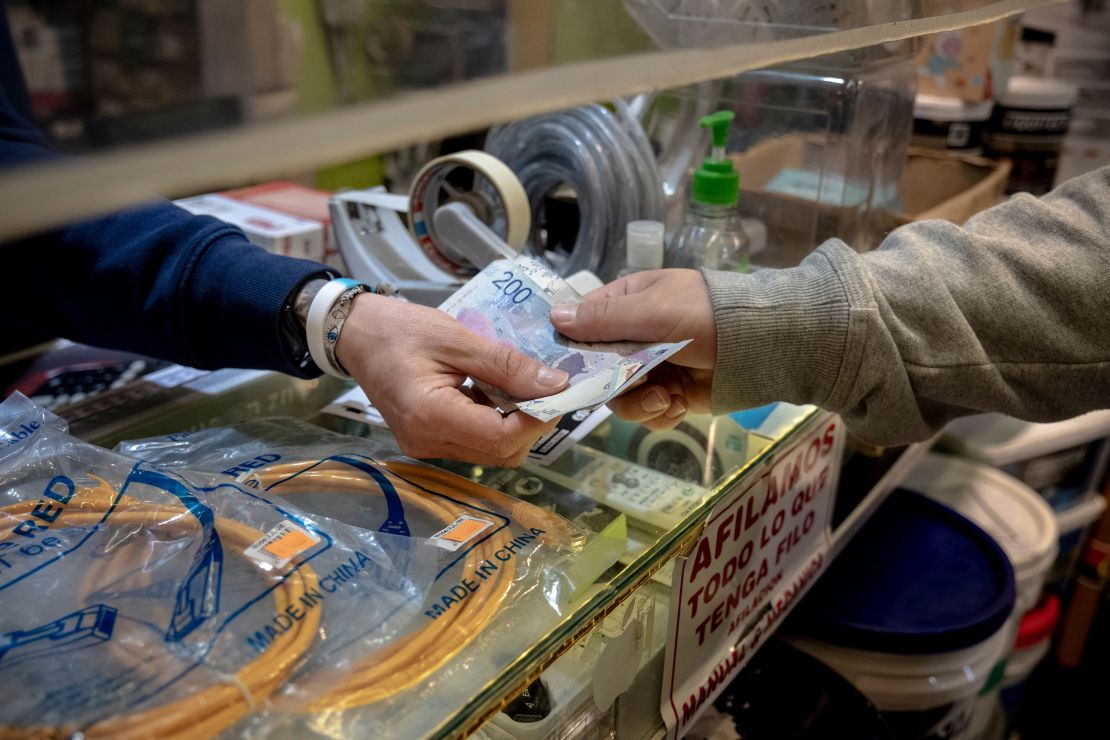 A worker receives Argentine peso banknotes in a shop in Buenos Aires on Sept. 26, 2023. Milei has proposed dollarizing Argentina.