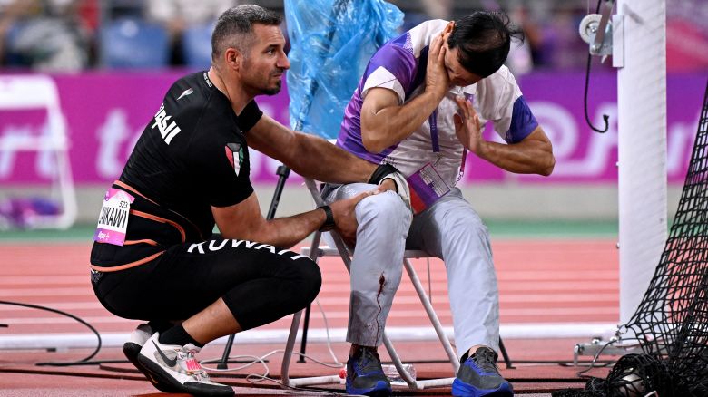 In this picture taken on September 30, 2023, an official reacts in pain after his leg was injured by a stray hammer thrown by Ali Zankawi (L) who attempts to stem the bleeding during the men's hammer throw final athletics event at the 2022 Asian Games in Hangzhou in China's eastern Zhejiang province.