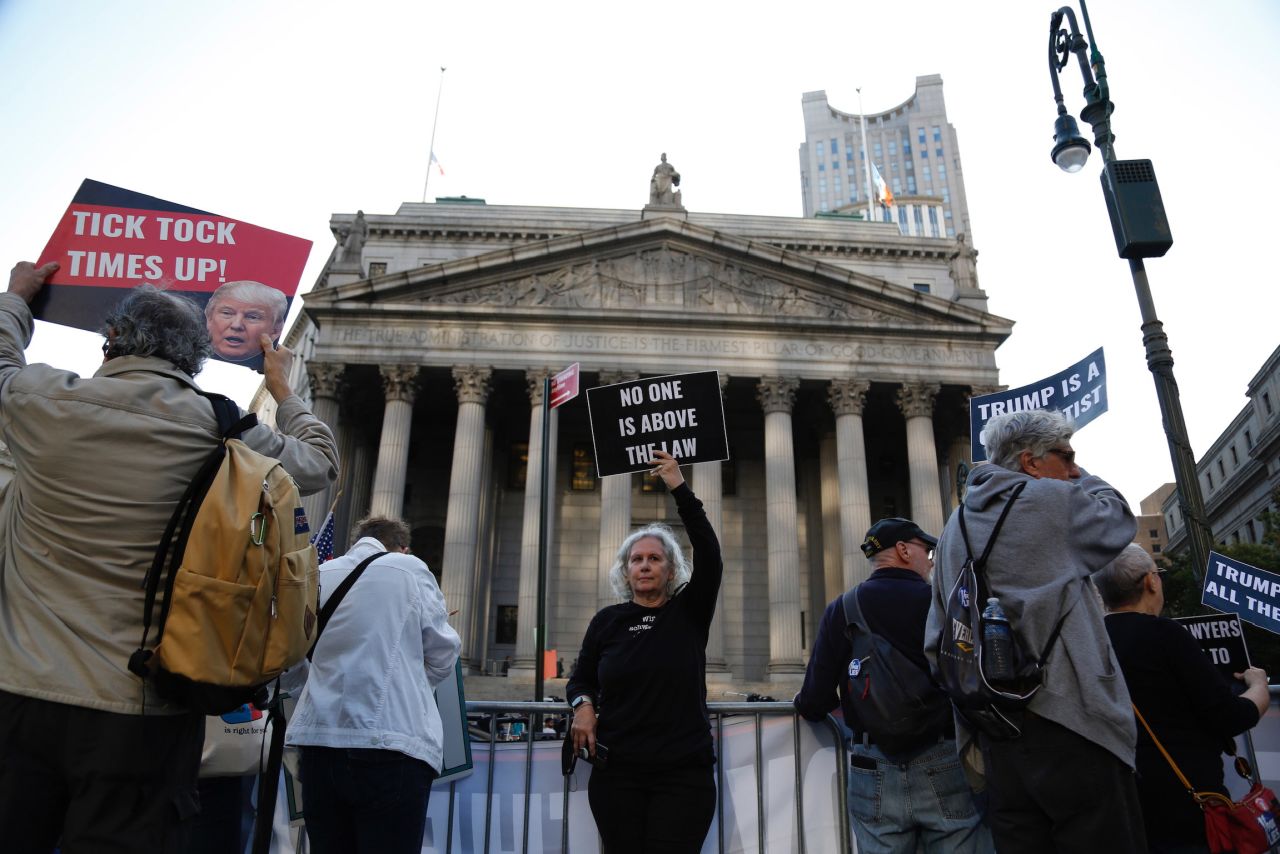 Demonstrators stand outside the court before the start of the trial on Monday.