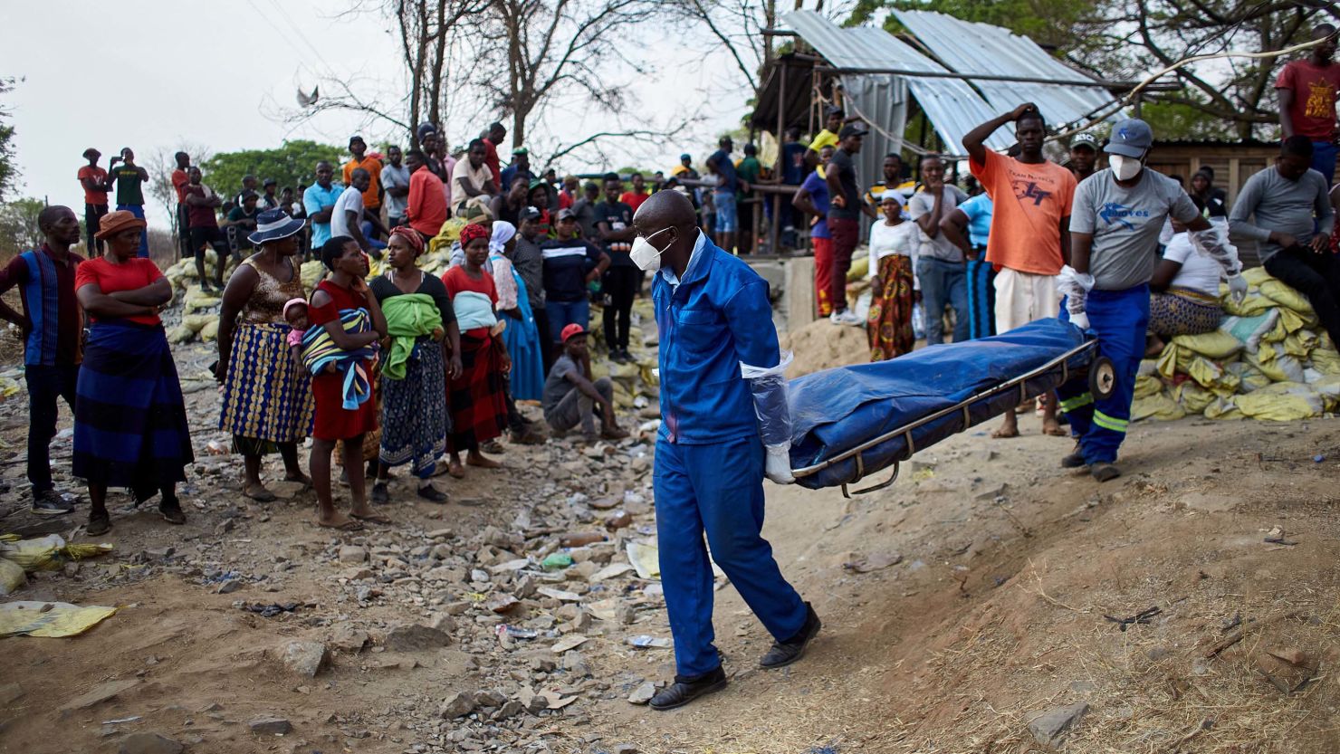 A crowd gathers to observe a rescue team carrying the body of a miner after a gold mine shaft collapsed at the Bay Horse mine in Chegutu, Zimbabwe on September 30, 2023.