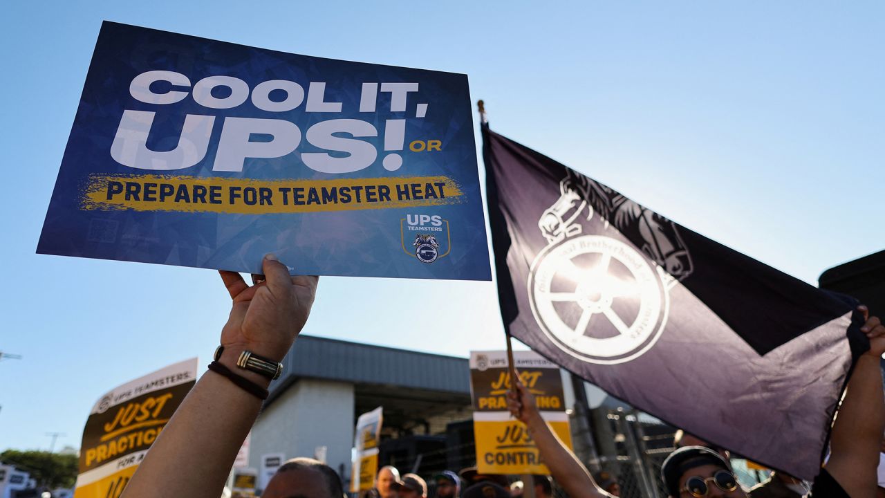 People hold placards during a rally held by Teamsters employed by UPS in downtown L.A., a strike deadline against the company neared this summer.