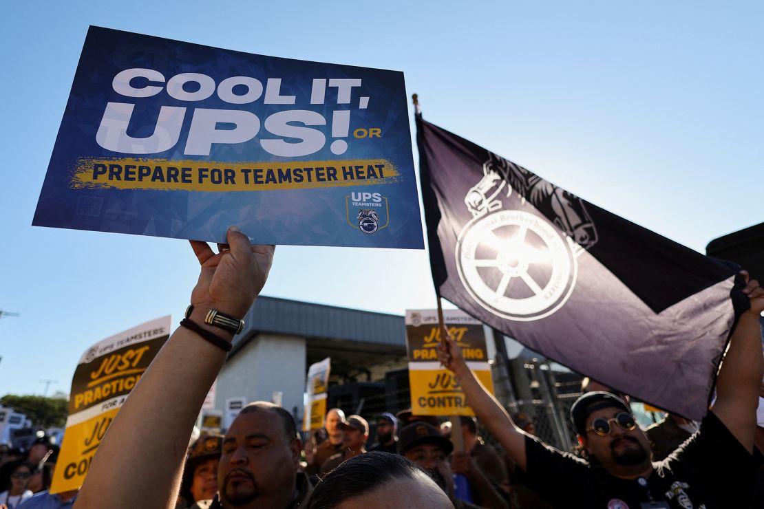 People hold placards during a rally held by Teamsters employed by UPS in downtown L.A., a strike deadline against the company neared this summer.