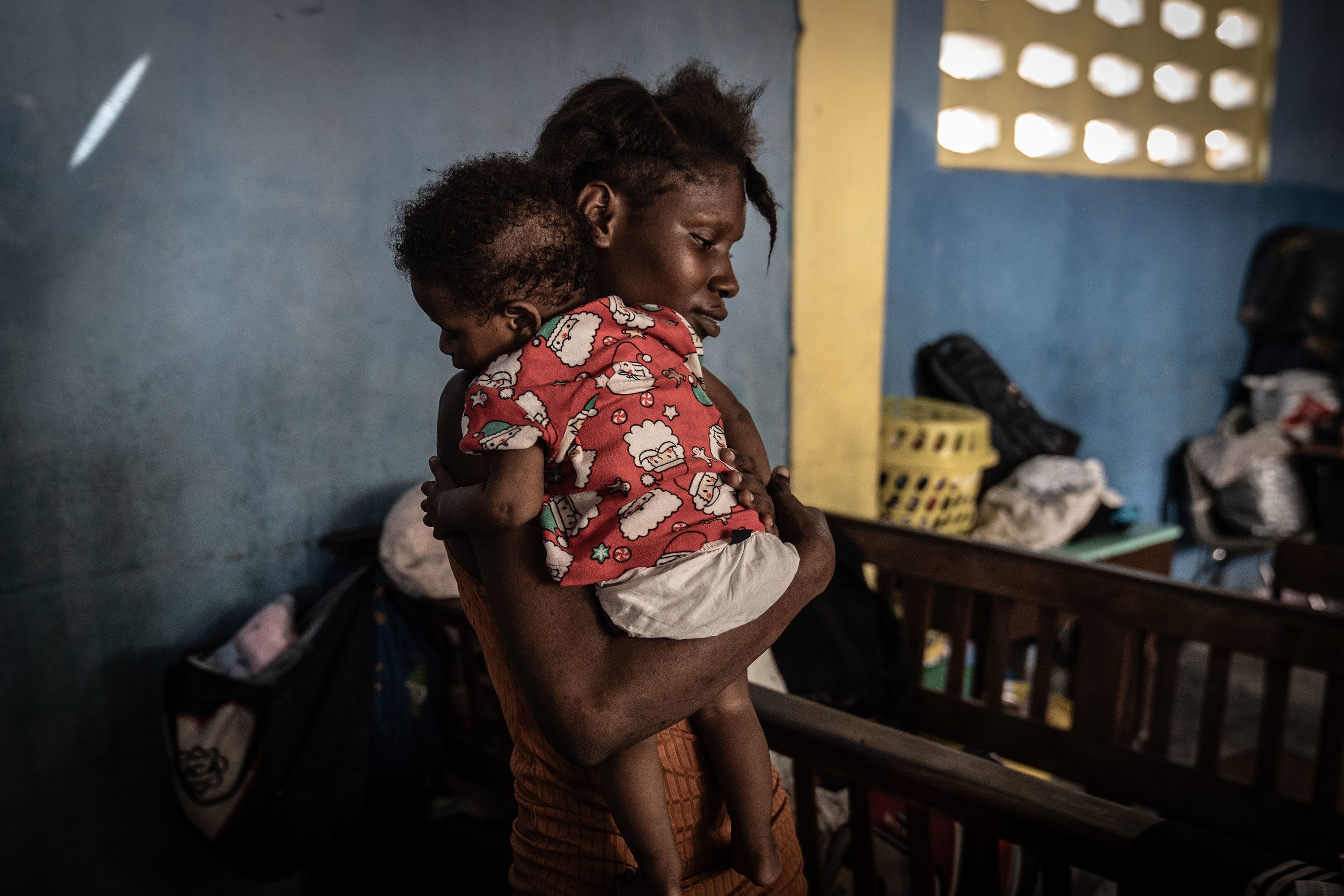 A mother holds her child inside a former church hall that was being used as a displacement shelter in Port-au-Prince, Haiti.