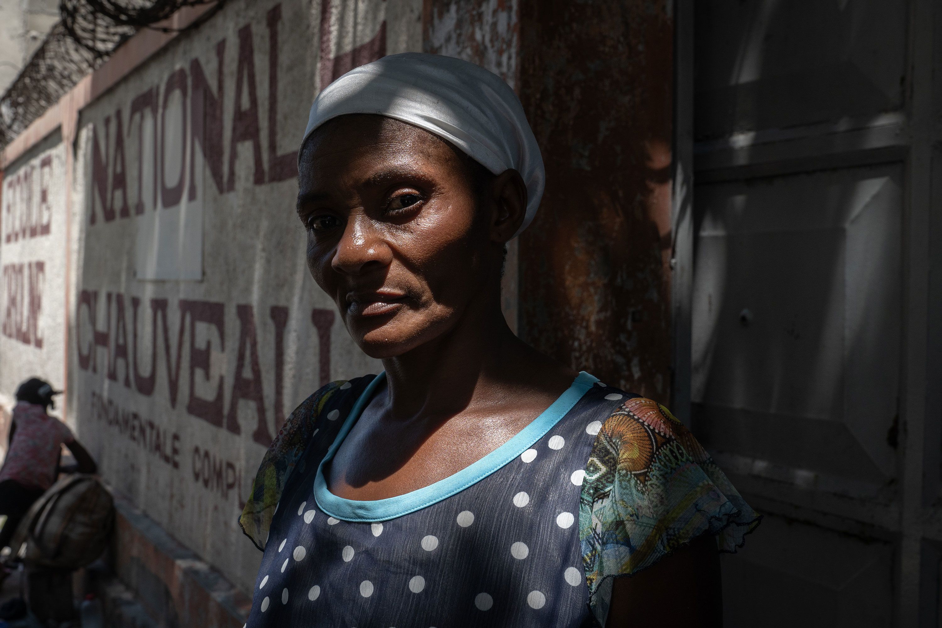 A Haitian woman waits for other family members at a settlement that was a former school.