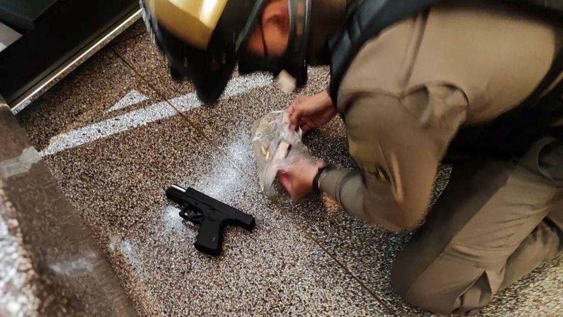 An officer inspects a gun. A police general said the suspected shooter still had ammunition when he was arrested.