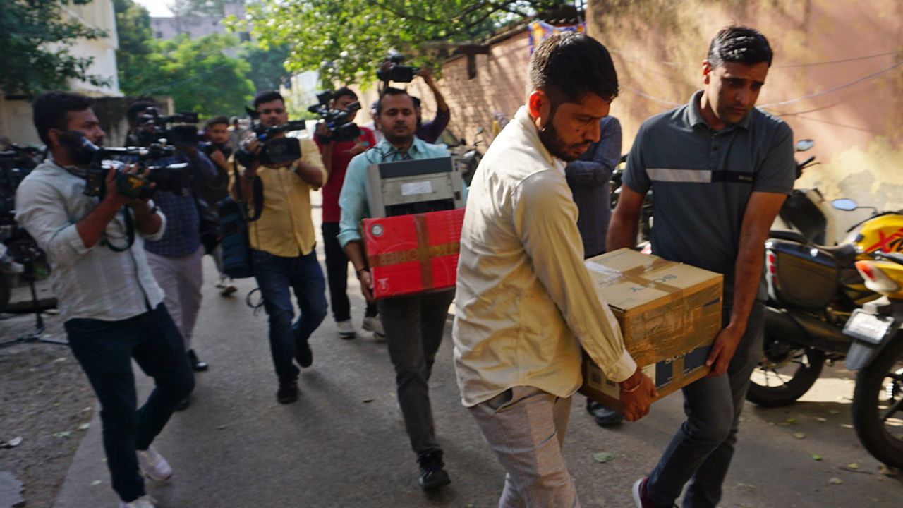 Security officers carry boxes of material confiscated after a raid on NewsClick in New Delhi, India, on Oct. 3.