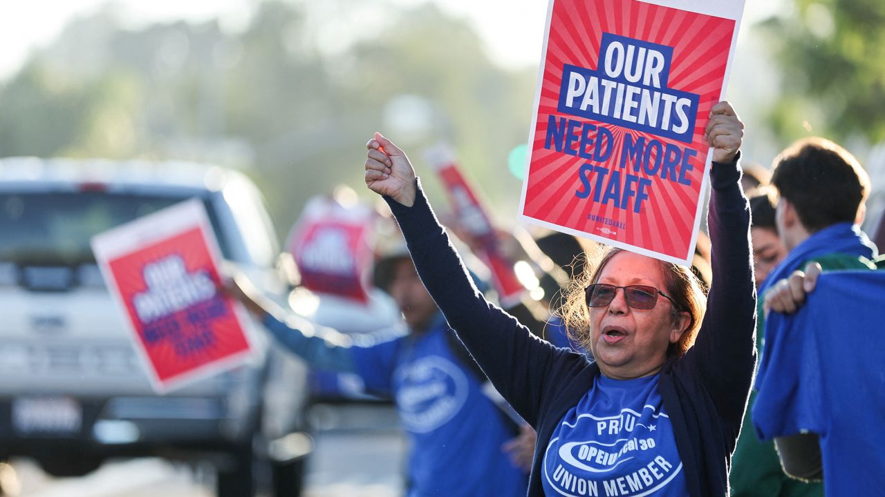 Una mujer en San Diego sostiene una pancarta, mientras una coalición de sindicatos de Kaiser Permanente que representa a 75.000 trabajadores de la salud inicia una huelga de tres días por un nuevo contrato.