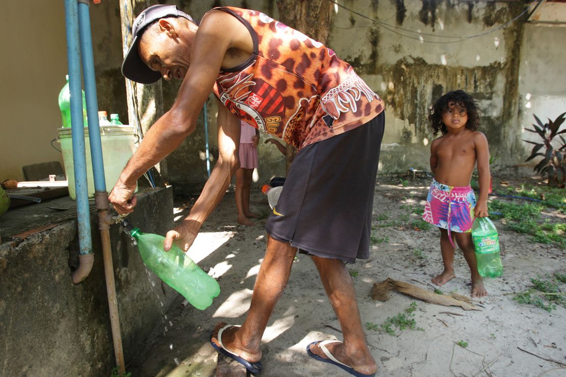 A man and child fill plastic bottles with water during a heat wave in Soure city at the Marajo island in Brazil on September 30.)