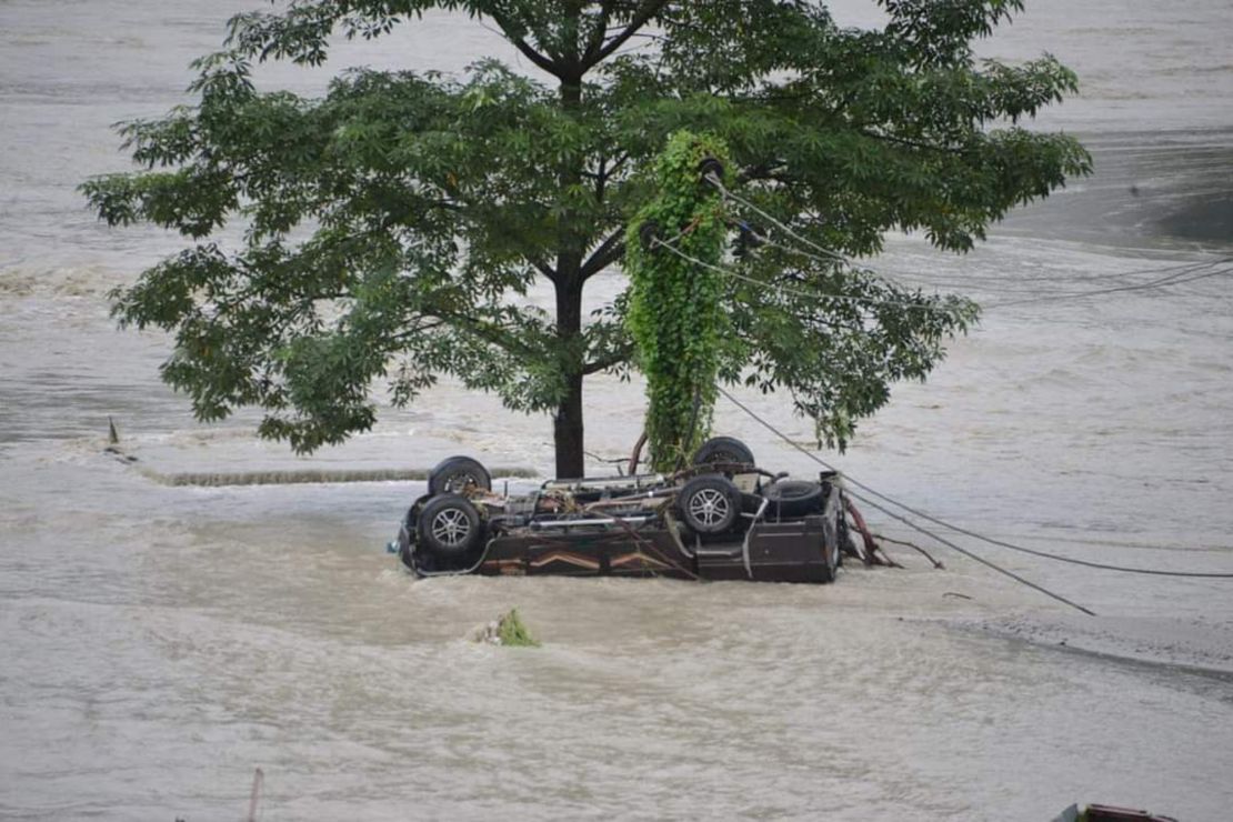 A vehicle that got washed away lies beneath a tree in Rangpo town in Sikkim, India.