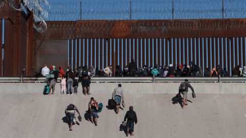 Migrants approach the border wall in Ciudad Juarez, Mexico, Wednesday, Dec. 21, 2022, on the other side of the border from El Paso, Texas. Migrants gathered along the Mexican side of the southern border Wednesday as they waited for the U.S. Supreme Court to decide whether and when to lift pandemic-era restrictions that have prevented many from seeking asylum. (AP Photo/Christian Chavez)