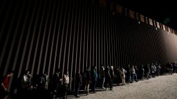 People line up against a border wall as they wait to apply for asylum after crossing the border from Mexico in July near Yuma, Arizona. 