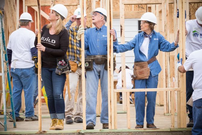 Trisha Yearwood helps Jimmy and Rosalyn Carter raise the walls of a'new Habitat home in Memphis Tennessee in 2015.