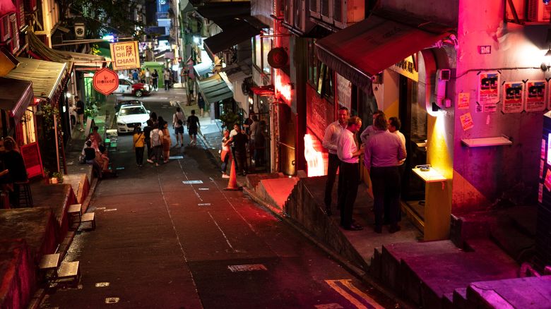 People stand outside a bar along a near empty street at night in Hong Kong, China, on October 5, 2023.
