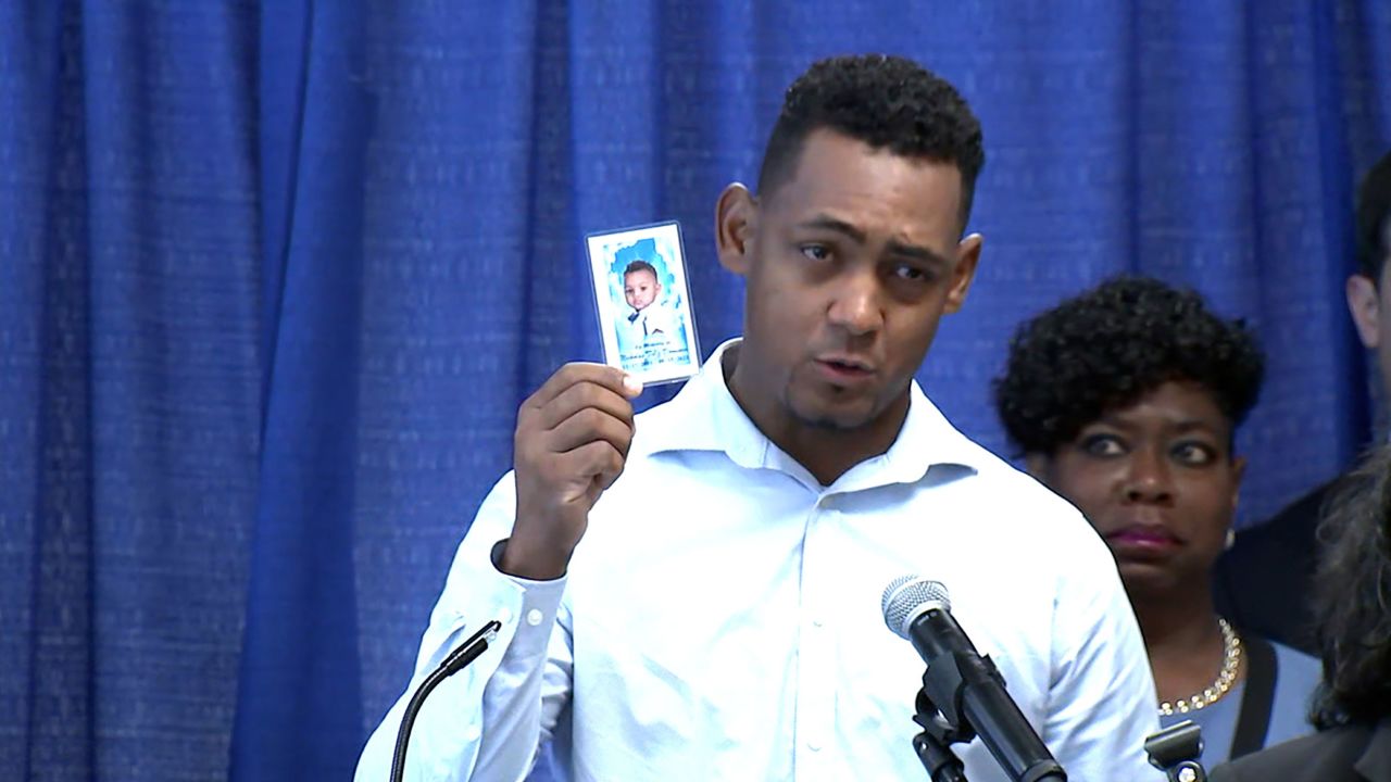 Otoniel Feliz holds a memorial photo of his 1-year-old son Nicholas Dominici. He spoke alongside Bronx District Attorney Darcel Clark, who announced indictments in connection with the boy's death.