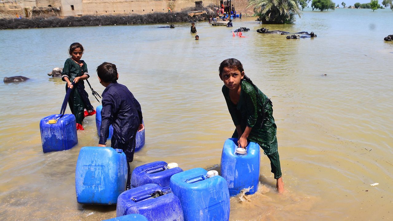 Des enfants transportent de l'eau potable à la suite d'inondations soudaines dans la province méridionale du Sind, au Pakistan, le 31 août 2022. 