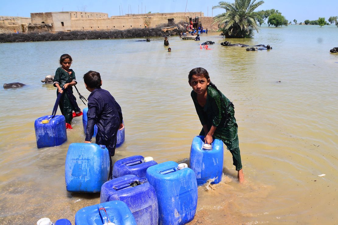 Children carry clean drinking water following flash flooding in southern Sindh province, Pakistan on August 31, 2022. 