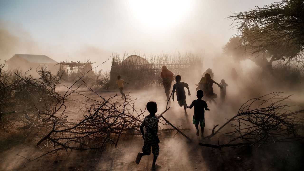 Children and women run among a cloud of dust at the village of El Gel, Ethiopia, on January 12, 2023. The last five rainy seasons since the end of 2020 failed, triggered the worst drought in four decades in Ethiopia, Somalia and Kenya. 