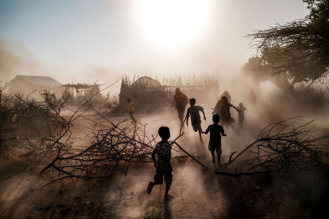 Children and women run among a cloud of dust at the village of El Gel, Ethiopia, on January 12, 2023. The last five rainy seasons since the end of 2020 failed, triggered the worst drought in four decades in Ethiopia, Somalia and Kenya. 