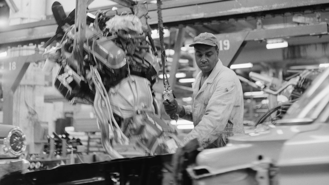 A black auto worker installs engines into Ford automobiles at the Ford Motor Company Willow Run plant in Detroit, Michigan, at a time in 1963 when African Americans rarely held such positions. 