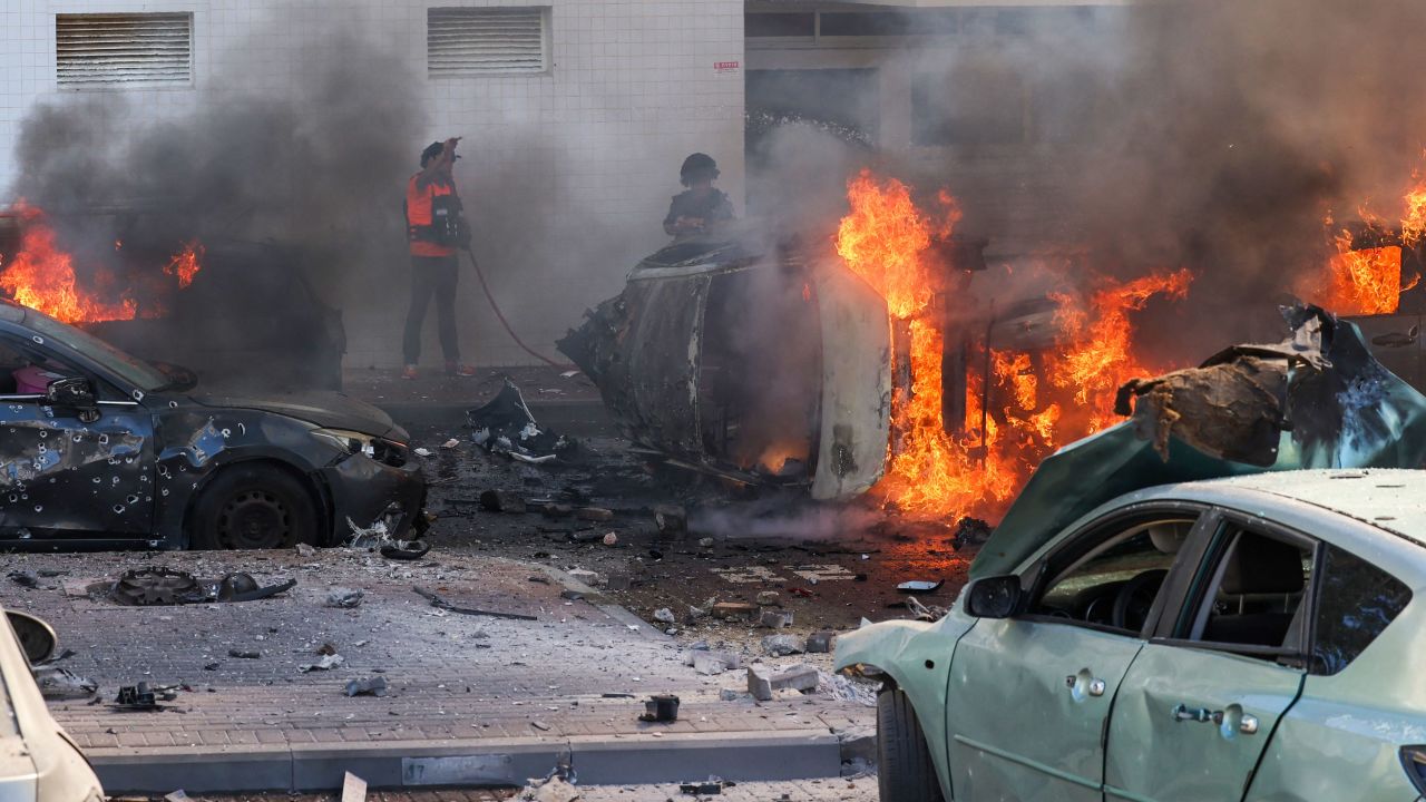 People try to extinguish fire on cars following a rocket attack from the Gaza Strip. 
