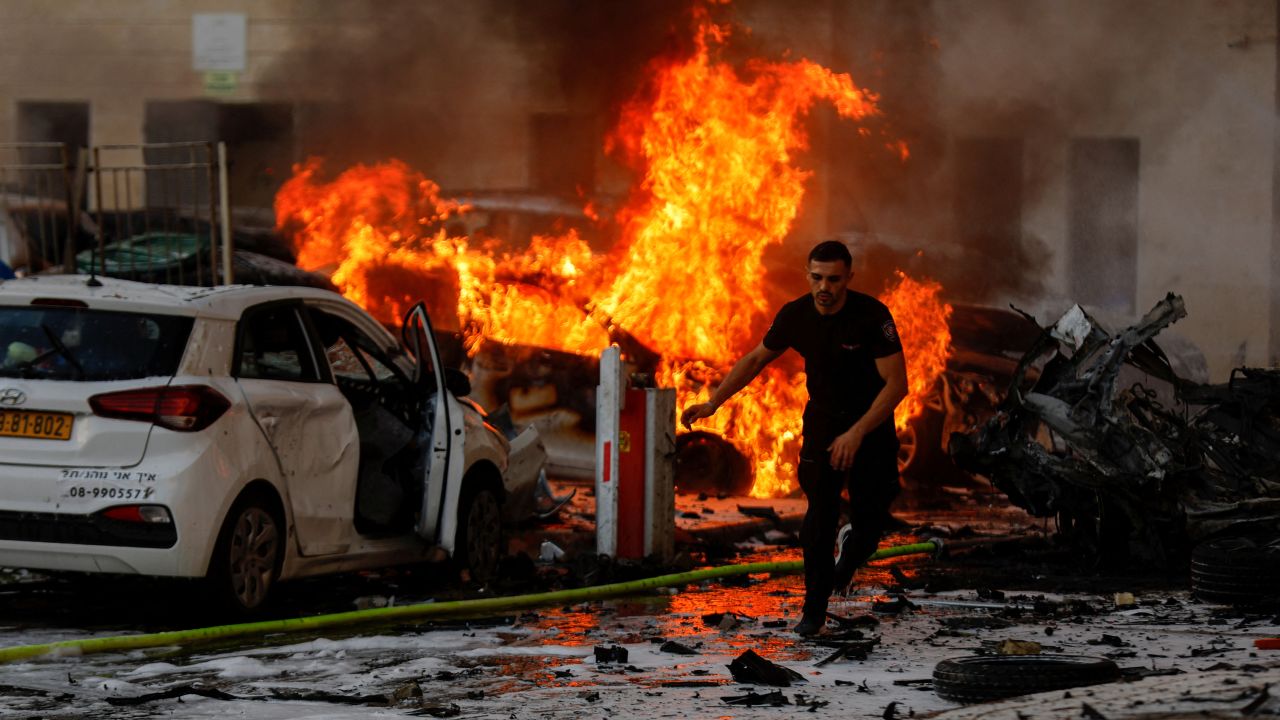 A man runs on a road as fire burns after rockets were launched from the Gaza Strip, in Ashkelon, Israel October 7, 2023. 
