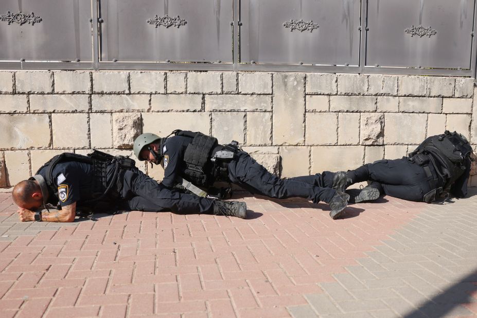 Members of the Israeli forces take cover in Ashkelon as sirens wail while rockets are fired from Gaza into Israel on Saturday.