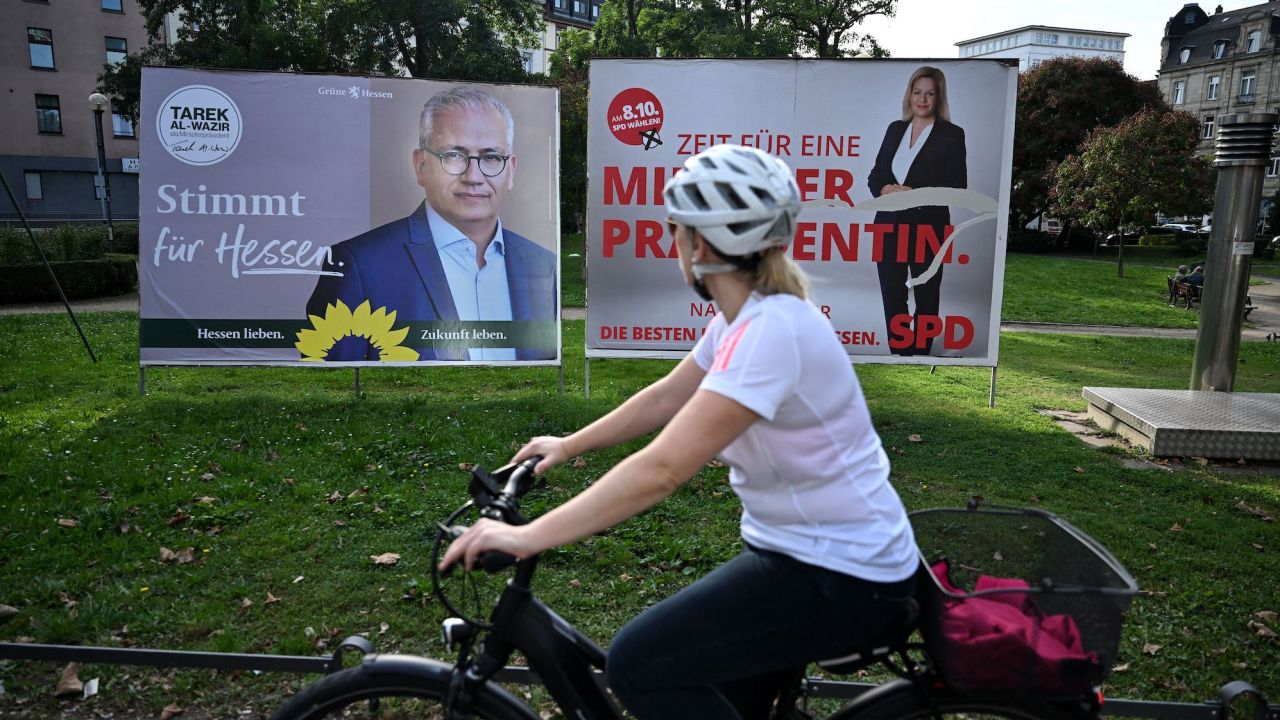 A woman rides a bicycle past election posters in Frankfurt.