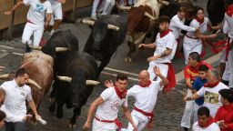 Participants run ahead of bulls during the "encierro" (bull-run) of the San Fermin festival in Pamplona, northern Spain, on July 14, 2023. Thousands of people every year attend the week-long festival and its famous 'encierros': six bulls are released at 8:00 a.m. evey day to run from their corral to the bullring through the narrow streets of the old town over an 850 meters (yard) course while runners ahead of them try to stay close to the bulls without falling over or being gored. (Photo by MIGUEL RIOPA / AFP) (Photo by MIGUEL RIOPA/AFP via Getty Images)