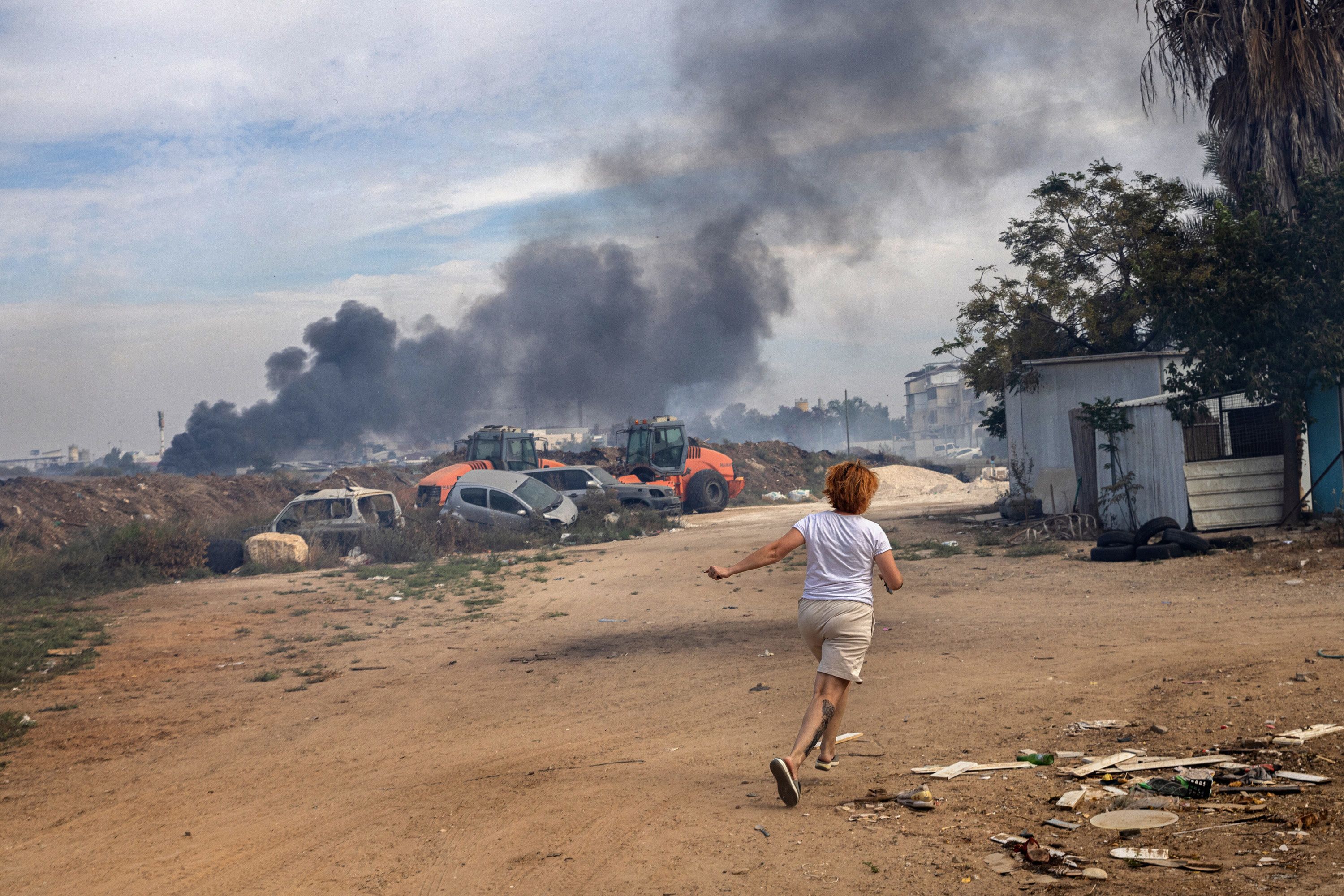 A woman runs to her family's reinforced concrete shelter moments after rocket sirens sounded in Ashkelon on October 7.