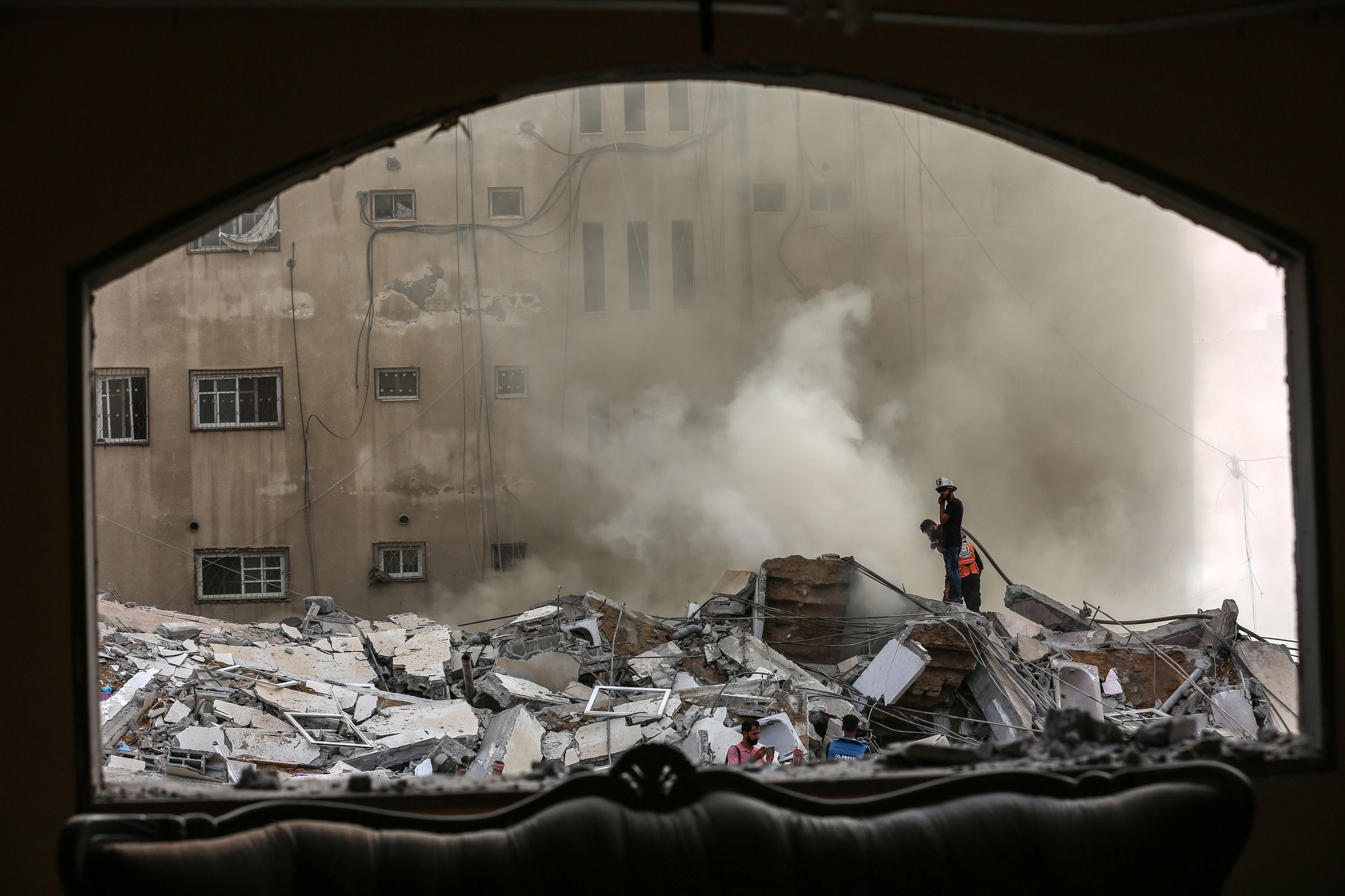 Palestinians inspect a destroyed building as emergency responders try to contain fires after Israeli jets bombed Gaza on October 7.