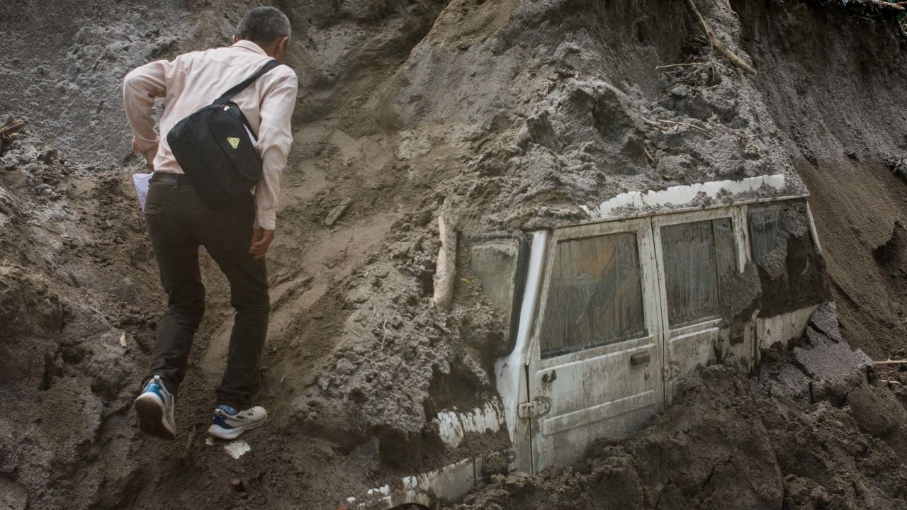A man walks next to a vehicle buried in mud due to floods, in Teesta Bazaar, Kalimpong District, West Bengal, India October 7, 2023. 