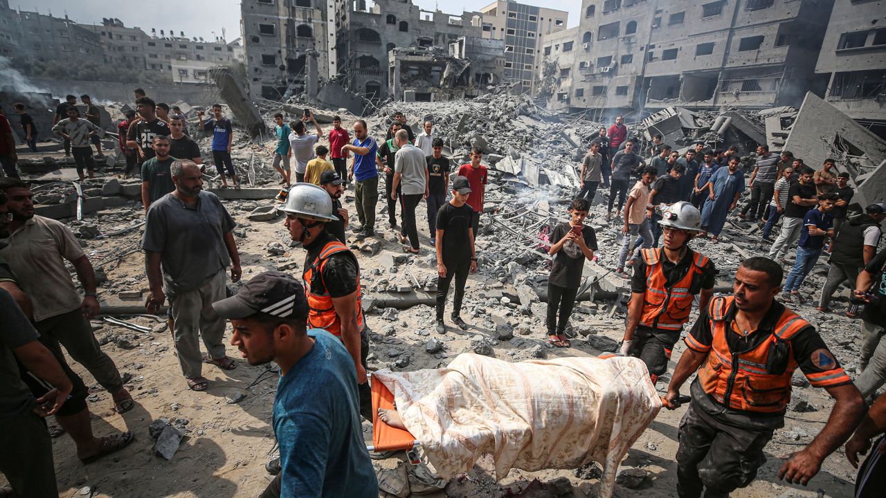 Palestinians carry a dead body after Israeli airstrikes hit al-Susi Mosque in Gaza on Monday.