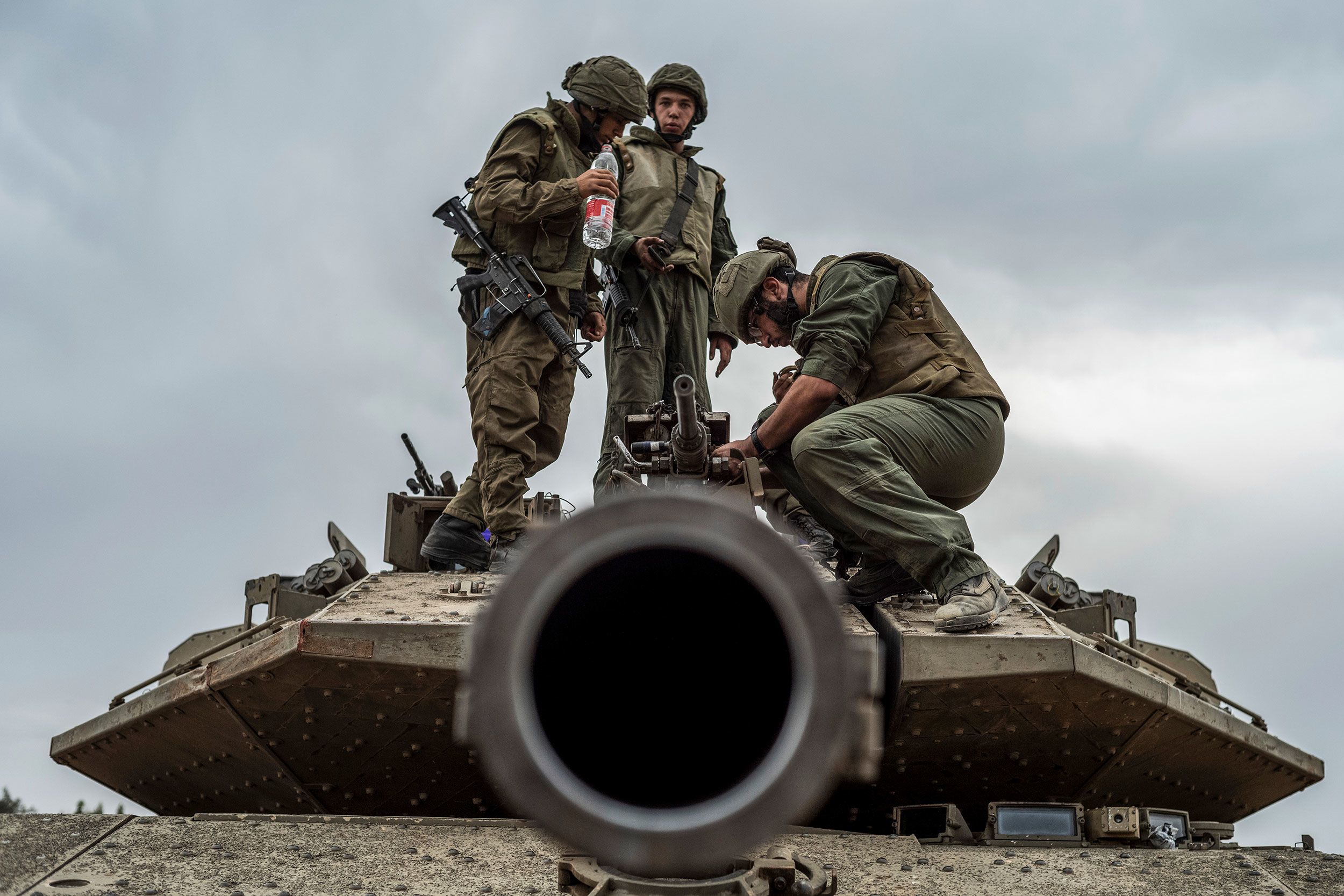 Israeli soldiers work on a tank at the border between Israel and Gaza on October 9.