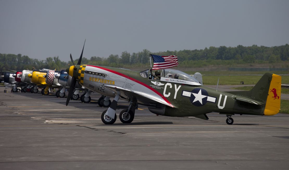 The pilot of a P51 Mustang waves the American flag after a practice flight with dozens of World War II era aircraft at Culpeper Regional Airport in Brandy Station, Virginia, May 7, 2015. Dozens of World War II era planes will fly past the National Mall in Washington, DC, on May 8, during the Arsenal of Democracy World War II Victory Capitol Flyover to commemorate the 70th anniversary of Victory in Europe (VE) Day. AFP PHOTO / ANDREW CABALLERO-REYNOLDS        (Photo credit should read Andrew Caballero-Reynolds/AFP via Getty Images)