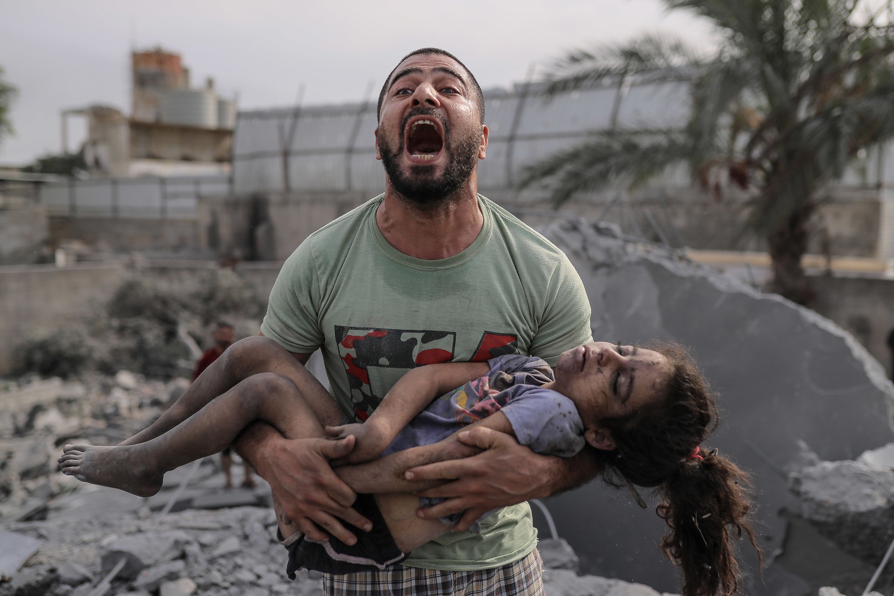 A Palestinian man reacts as he carries the body of his cousin who was pulled from the rubble after Israeli airstrikes in Gaza City on Monday, October 9.