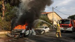 A firefighter douses a car blaze in the southern Israeli city of Ashkelon after a rocket attack from Gaza on October 9, 2023. Stunned by the unprecedented assault on its territory, a grieving Israel has counted over 700 dead and launched a withering barrage of strikes on Gaza that have raised the death toll there to 493 according to Palestinian officials. (Photo by Menahem KAHANA / AFP) (Photo by MENAHEM KAHANA/AFP via Getty Images)