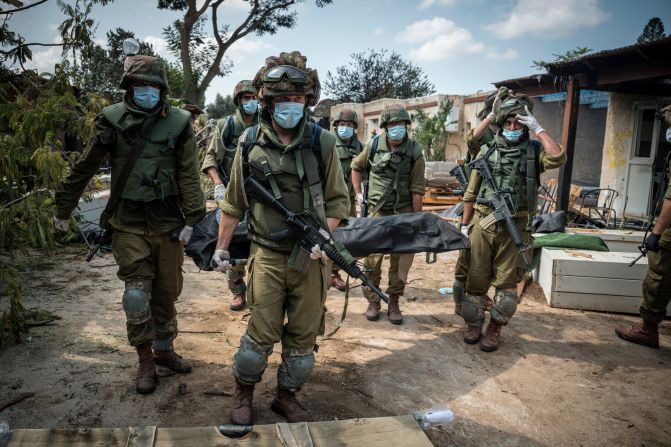 Israeli soldiers carry a body on October 10 in Kfar Aza, a village in Israel just across the border from Gaza. Hamas militants carried out a "massacre" in Kfar Aza during their attacks over the weekend, <a href="index.php?page=&url=https%3A%2F%2Fwww.cnn.com%2Fmiddleeast%2Flive-news%2Fisrael-hamas-war-gaza-10-10-23%2Fh_7867b7563e54a0b29dddeada7e4c2722" target="_blank">the Israel Defense Forces told CNN</a>.