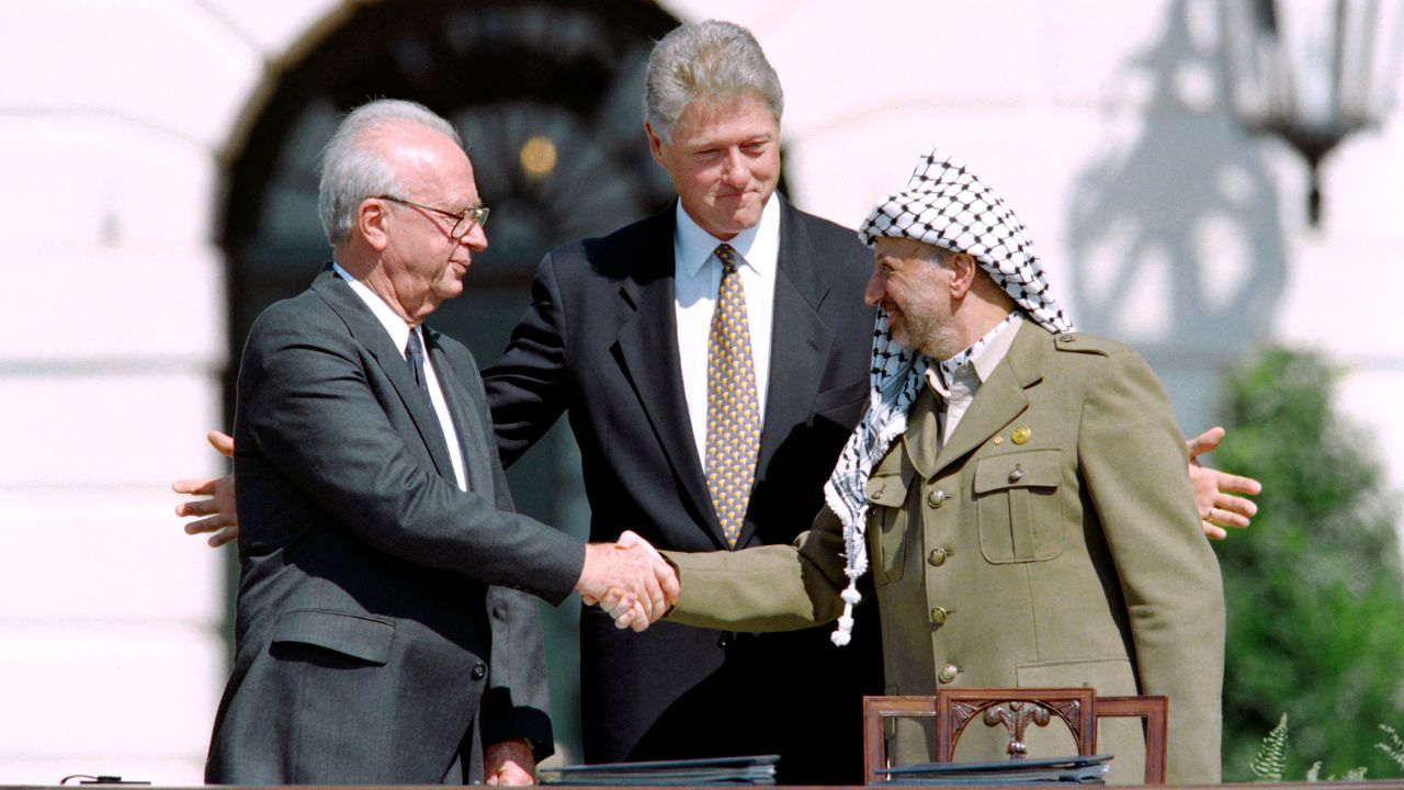 Clinton stands between the Palestinian leader Yasser Arafat and Israeli Prime Minister Yitzahk Rabin as they shake hands for the first time on September 13, 1993, at the White House.
