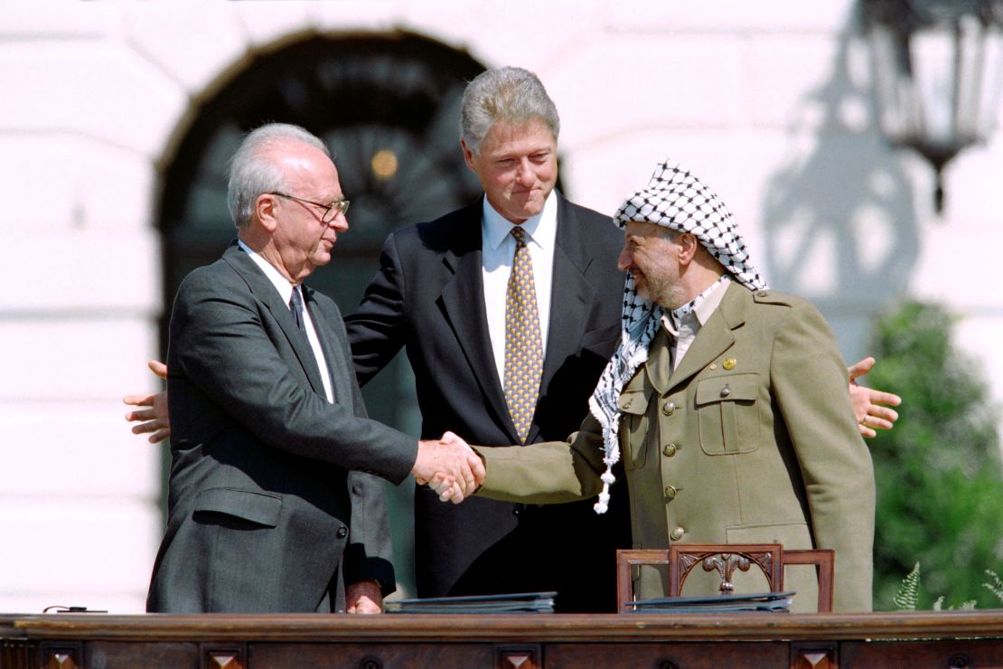 Clinton stands between the Palestinian leader Yasser Arafat and Israeli Prime Minister Yitzahk Rabin as they shake hands for the first time on September 13, 1993, at the White House.