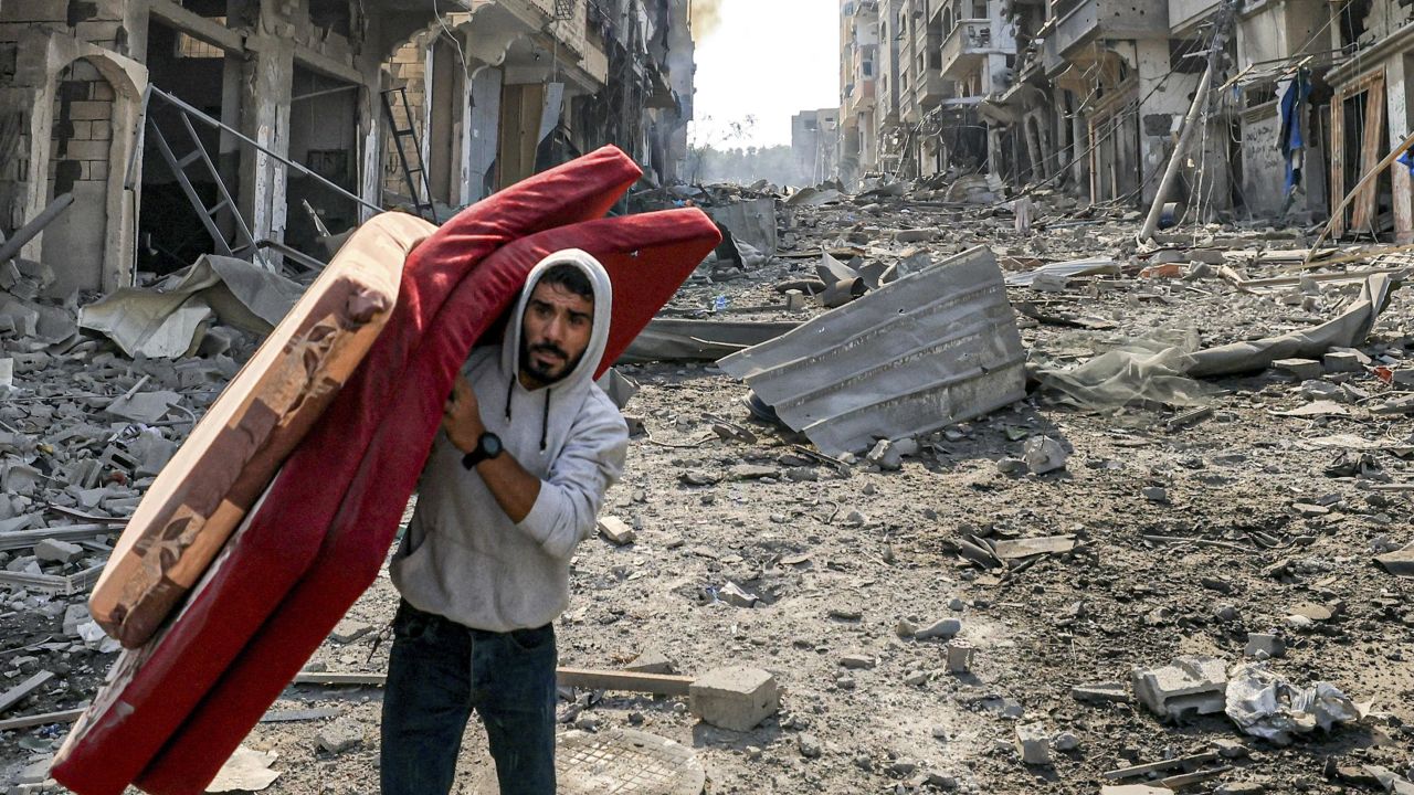 A man carries mattresses through rubble in Gaza's Jabalia refugee camp on October 11, following overnight Israeli airstrikes.
