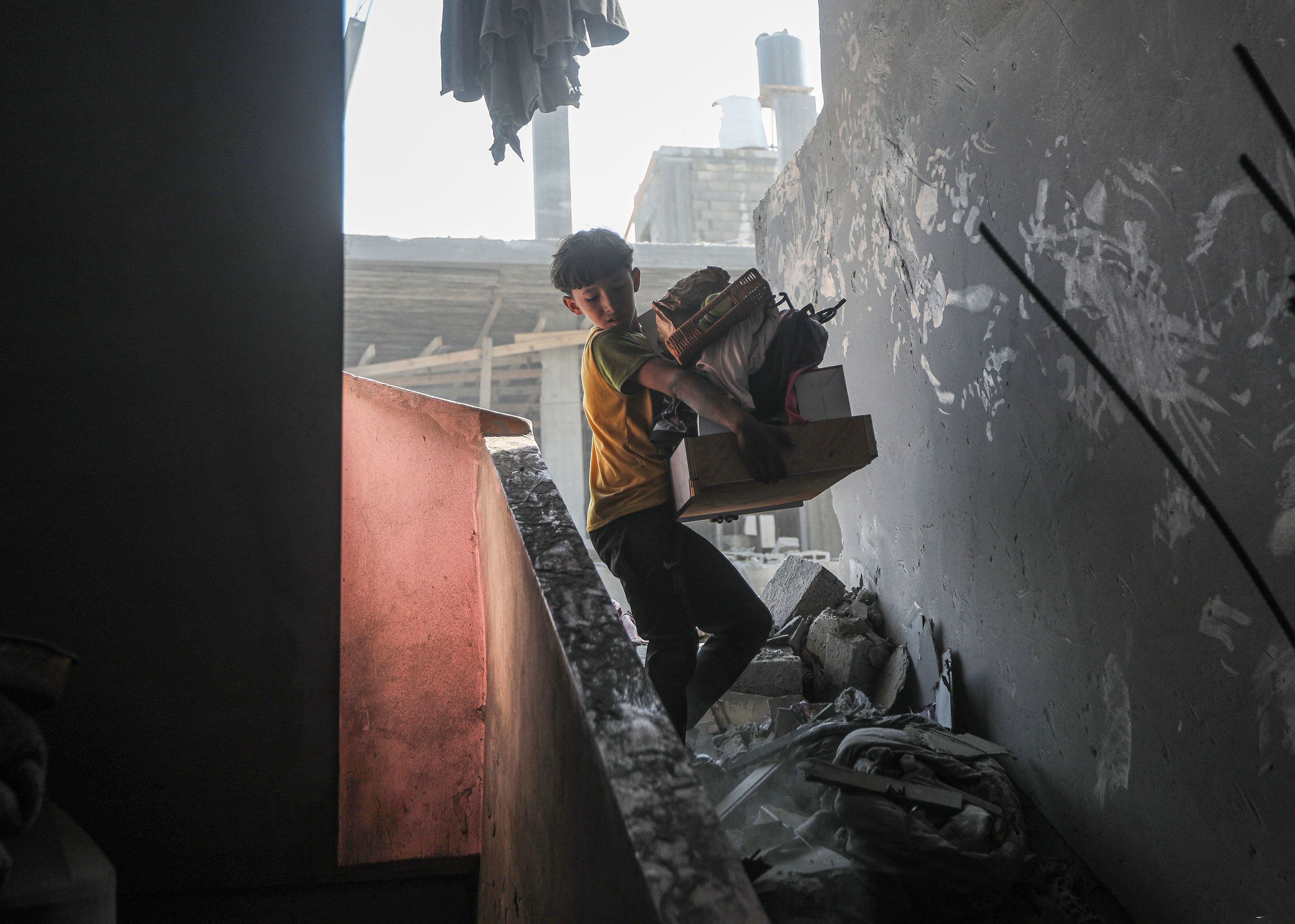A boy carries salvaged belongings from the wreckage of his family's home in Khan Younis, Gaza, on October 11.