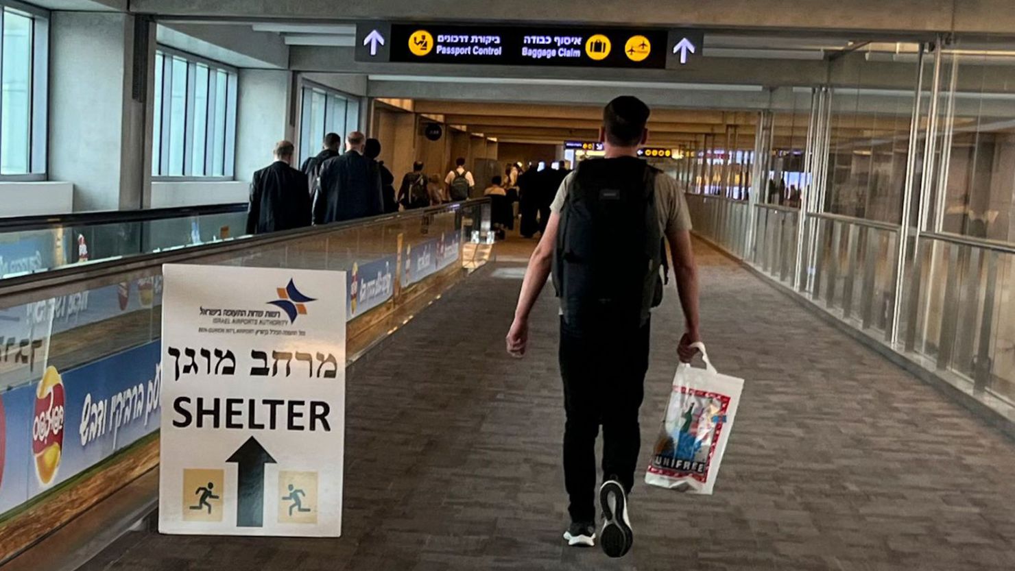 A sign informing passengers about the location of rocket shelters is set-up in a hallway as travelers arrive at Ben Gurion International Airport near Tel Aviv on October 10, 2023. 