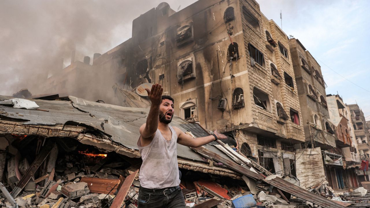 A man reacts outside a burning collapsed building following Israeli bombardment in Gaza City on October 11.