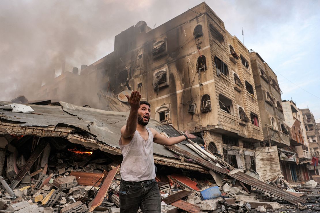 A man reacts outside a burning collapsed building following Israeli bombardment in Gaza City on October 11.