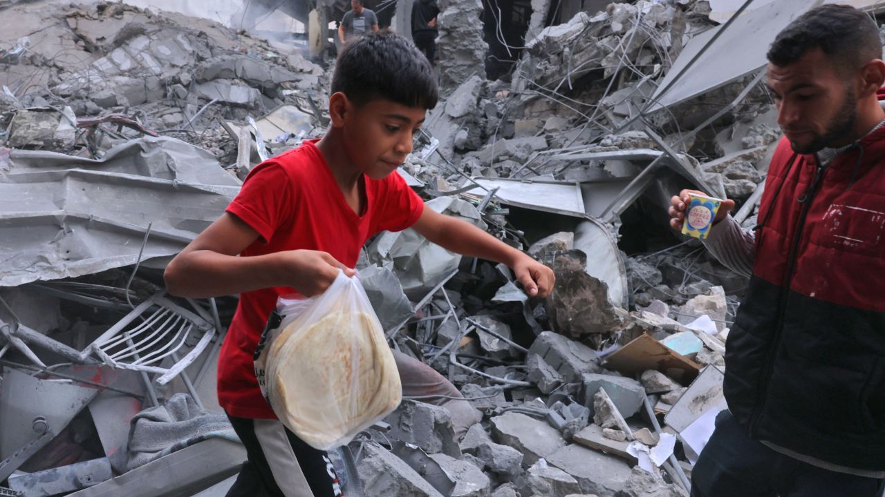 A Palestinian youth carries bread amid the rubble of the city center of Khan Yunis in the southern Gaza Strip following Israeli shelling on October 10.