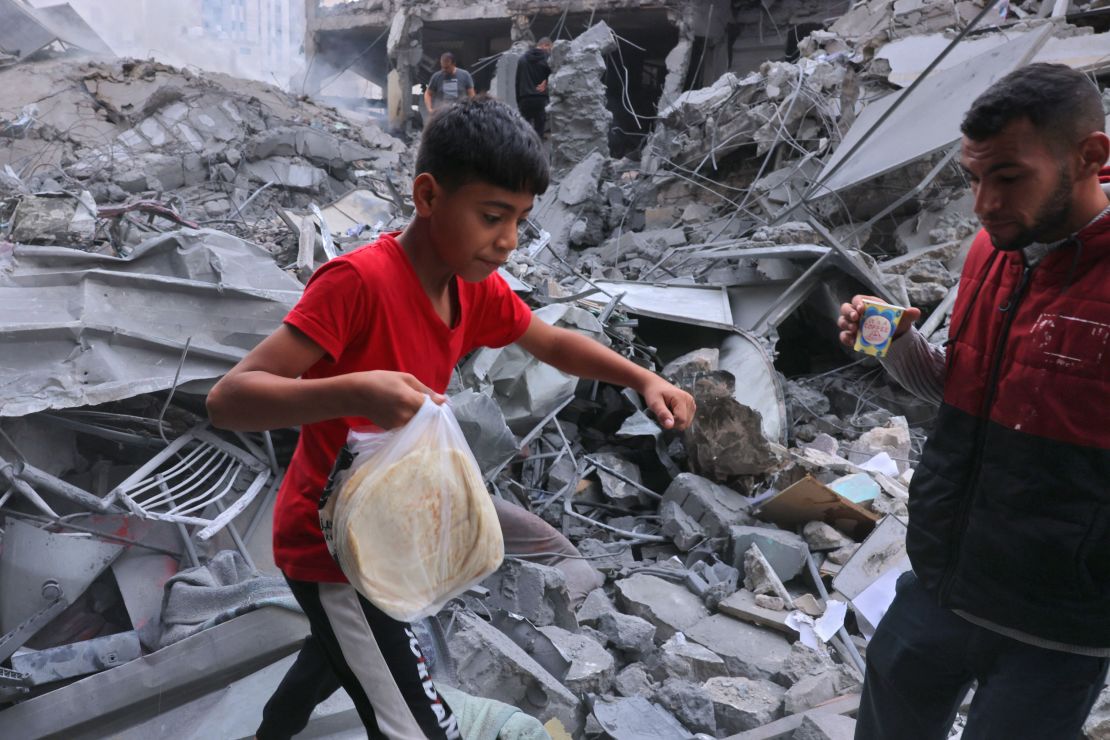 A Palestinian youth carries bread amid the rubble of the city center of Khan Yunis in the southern Gaza Strip following Israeli shelling on October 10.
